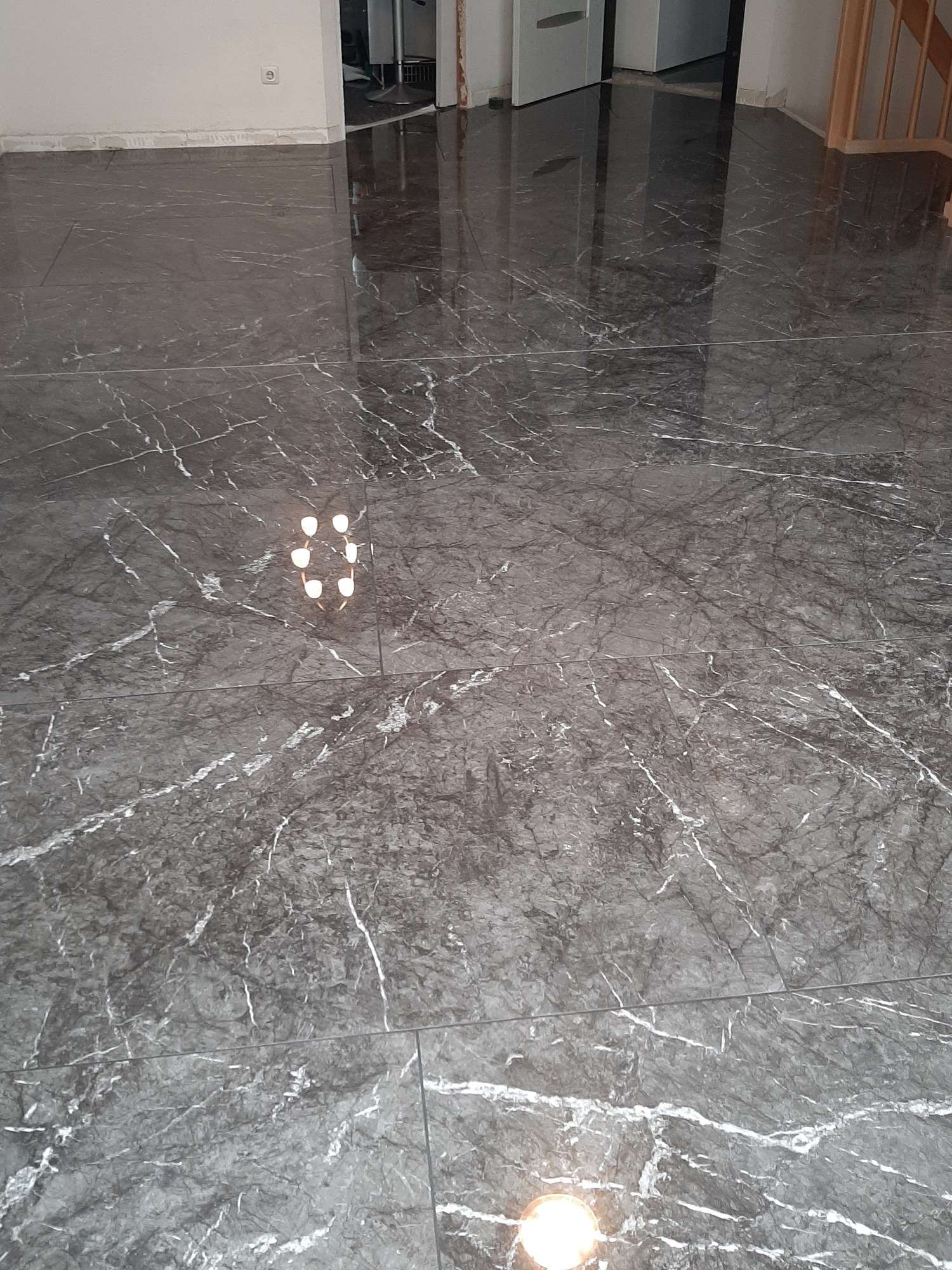 Błyszcząca posadzka z dużych płytek imitujących szary marmur z białymi żyłkami